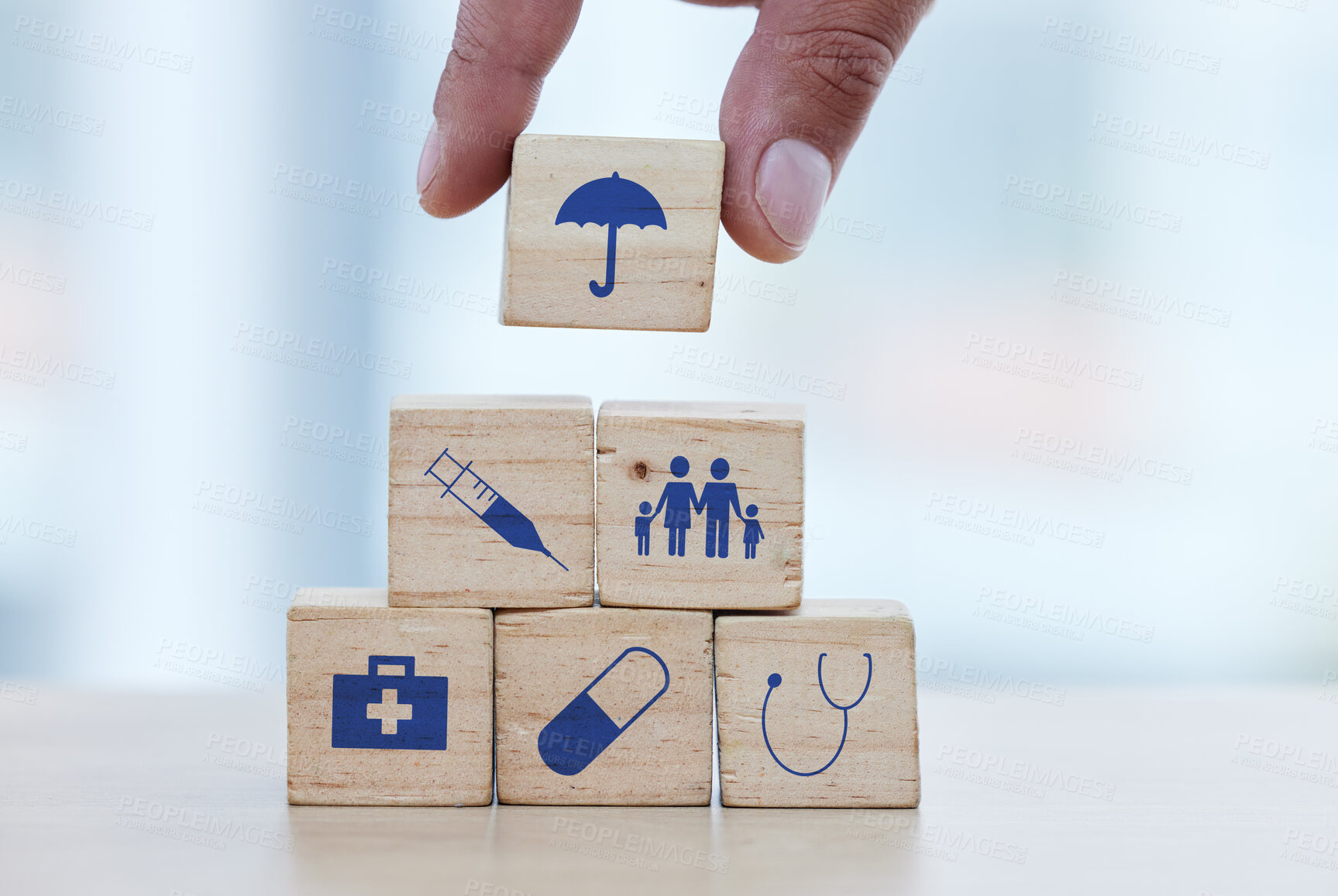 Buy stock photo Hands, wood and building blocks on table for insurance, healthcare or a safe healthy foundation. Hand of doctor putting small wooden block, object or icons with umbrella to build medical investment