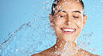Water splash, smile and skincare, woman with mockup and product placement on clean blue background. Dermatology, fresh and happy person cleaning face with marketing for luxury anti ageing cosmetics.