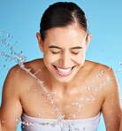 Face wash, skincare and woman isolated on blue background for beauty, cosmetics cleaning and happy. Smile of a person or model with water splash for dermatology wellness and aesthetic in studio