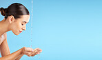 Beauty, water and mockup with a model woman cleaning her face in studio on a blue background for hygiene. Skincare, hands and mock up with an attractive young female washing her skin for hydration