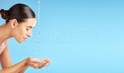 Buy stock photo Beauty, water and mockup with a model woman cleaning her face in studio on a blue background for hygiene. Skincare, hands and mock up with an attractive young female washing her skin for hydration