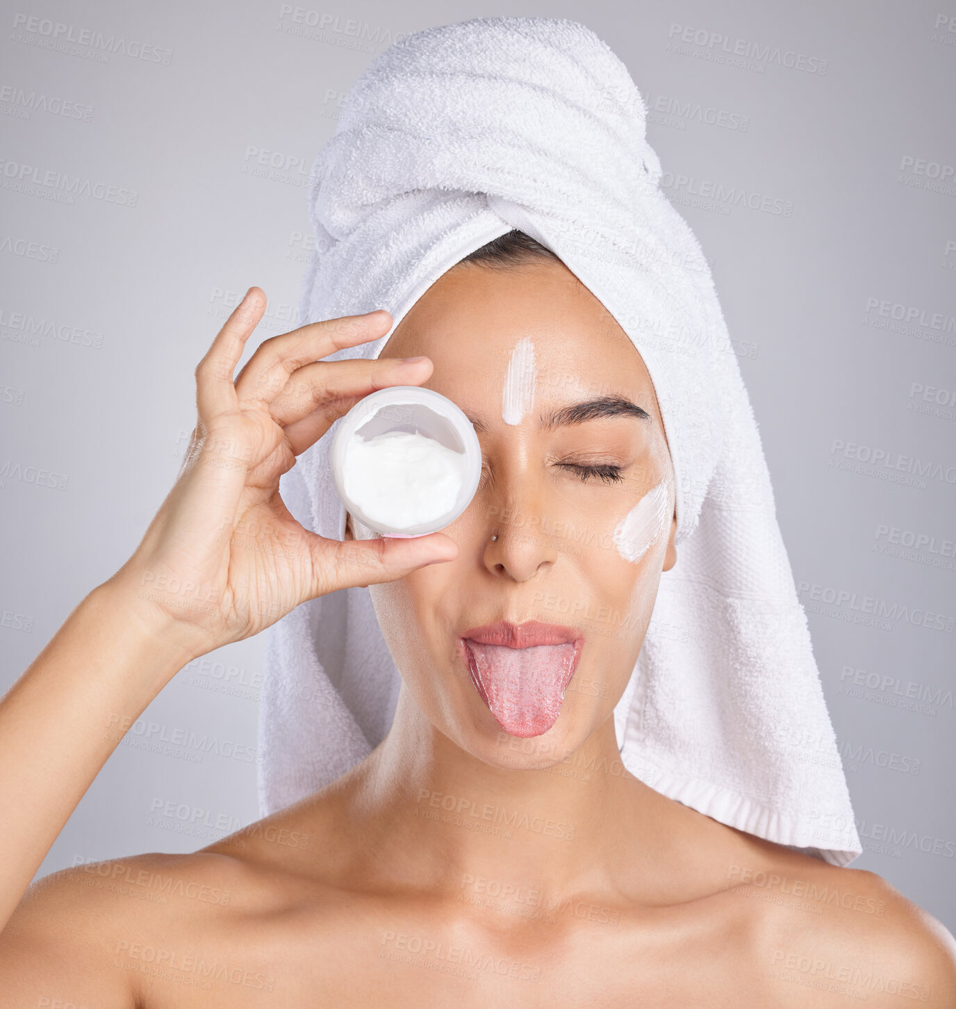 Buy stock photo Woman, skincare cream and tongue in studio for wellness, health and cosmetic health with towel by background. Young healthy model, lotion and funny face for facial, self care and comic by backdrop