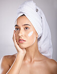 Woman, head towel and cream for cosmetics, makeup and face detox on grey studio background. Young female, lady and organic facial for treatment, clear and healthy skin for natural beauty and skincare