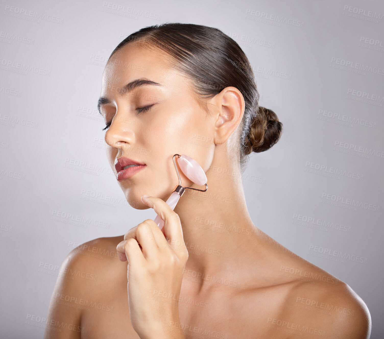 Buy stock photo Rose quartz, face roller and woman skincare of a model relax from facial spa treatment. Isolated, studio background and young person busy with dermatology, self care and beauty treatment for skin