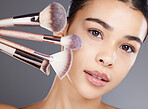 Makeup, portrait or woman brushes her face with facial cosmetics or luxury skincare products. Glow, aesthetic or beautiful girl model grooming in self care routine isolated on studio background 