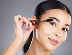 Portrait, eyelash and brush for makeup, cosmetics and beauty with girl with grey studio background. Face, eyes and salon equipment for grooming routine, wellness or confidence with brows and mascara