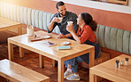 Coffee, cafe and barista couple at table drinking, talking and laughing at funny meme. Small business, owners or happy man and woman on break with caffeine or espresso while having comic conversation