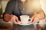 Coffee, cafe and hands of waiter with cup on table in restaurant. Small business, cappuccino art or barista, man or server holding fresh, delicious or hot mug of caffeine or espresso in shop or store