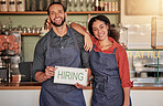 Small business, portrait or couple with a hiring sign for job vacancy offer at a cafe or coffee shop. Recruitment, marketing or happy entrepreneurs smile standing with an onboarding message in store