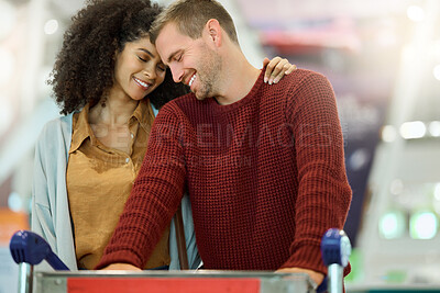 Buy stock photo Love, travel and couple at airport with luggage, bonding and affection. Romance, diversity and care of happy man and woman embrace while pushing suitcase trolley and preparing for vacation flight.