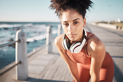 Buy stock photo Portrait, exercise and black woman rest, beach and training outdoor, headphones and wellness. African American female tired, lady and runner with headset, exhausted and workout for cardio and seaside