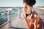 Thinking, fitness and tired with a black woman runner on the promenade for cardio or endurance exercise. Running, workout or health with an attractibe young female athlete training outdoor by the sea