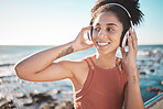 Music, thinking and fitness with a sports black woman by the sea during her running workout at the sea. Exercise, training and radio with a female runner listening to audio by the ocean in summer