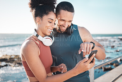 Buy stock photo Fitness, couple and phone with smile for social media, communication or discussion relaxing by the beach. Happy man and woman smiling in happiness looking or browsing on smartphone by the ocean coast