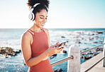 Black woman at beach, headphone and phone with fitness, runner listening to music for sports motivation. Happy, streaming online with podcast or radio, smartphone and running by sea with calm outdoor