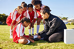 Sports, injury and children soccer team with their coach in a huddle helping a girl athlete. Fitness, training and kid with a sore, pain or muscle sprain after a match on an outdoor football field.