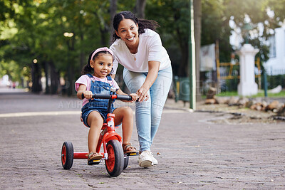 Buy stock photo Mother, kid and bicycle teaching with training wheels for learning, practice or safety at the park. Happy mom helping little girl to ride a bike with smile for proud playful moments in the outdoors