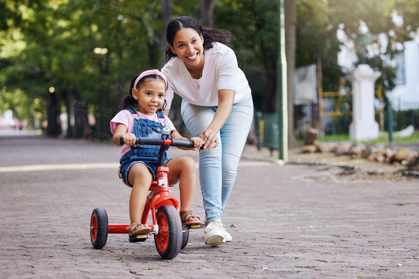 Buy stock photo Mother, kid and bicycle teaching with training wheels for learning, practice or safety at the park. Happy mom helping little girl to ride a bike with smile for proud playful moments in the outdoors