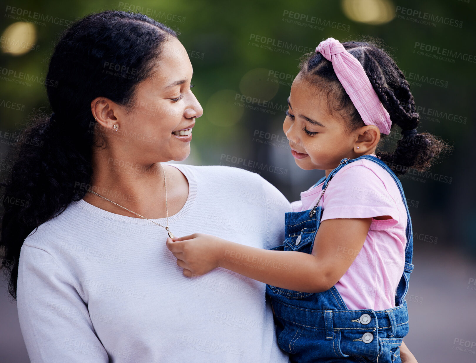 Buy stock photo Family, mother and carrying little girl with smile for outdoor bonding and hugging at a park. Motherhood support, care and love with daughter, child or kid touching necklace or jewelry on mom outside