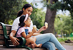 Summer, garden and ice cream with a mother and daughter bonding together while sitting on a bench outdoor in nature. Black family, children and parkl with a woman and girl enjoying a sweet snack