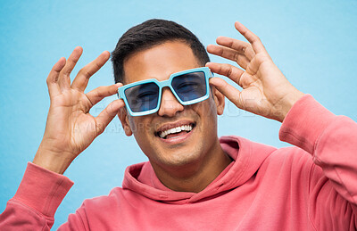 Buy stock photo Happy, man with sunglasses and smile with face, trendy fashion and happiness with freedom isolated on blue background. Funky, retro and wellness, hipster person in studio with vintage designer brand