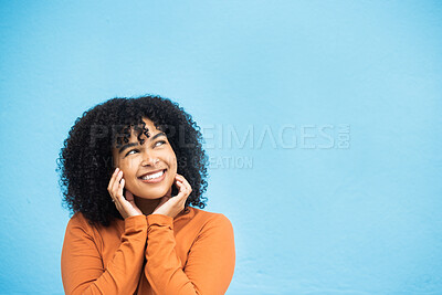 Buy stock photo Thinking, happy and mockup with a black woman on a blue background in studio for branding or product placement. Idea, smile and mock up with an attractive young female looking thoughtful on space