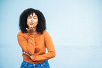 Portrait, kiss and woman flirting in studio for fun, playful and personality against a blue background. Black woman, blowing kiss and emoji for kissing, attraction and desire while standing isolated