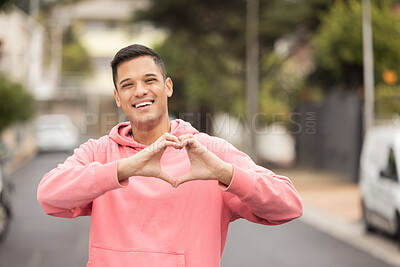Buy stock photo Portrait, hands and heart by man in city, happy and relax, travel and journey on blurred background. Face, traveler and emoji, hands and shape by handsome guy showing icon, love and smile for Mexico