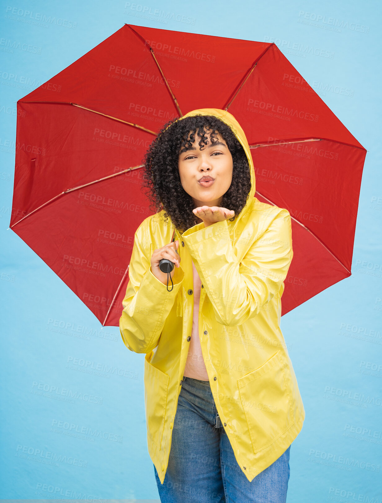 Buy stock photo Portrait, black woman and umbrella in a city for kiss, travel and flirting on a solo trip against wall background. Face, blowing kiss and girl traveler relax in rainfall, excited and emoji gesture 