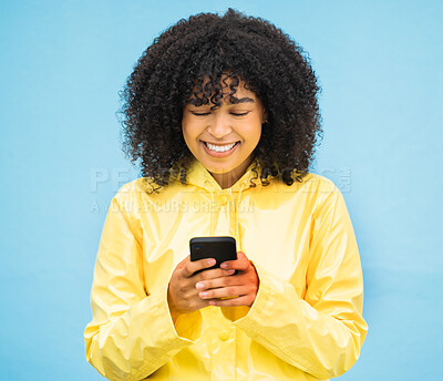 Buy stock photo Black woman, rain coat and phone with a person in winter with blue studio background. Isolated, happiness and social media communication of a female ready to text and connect on a weather app
