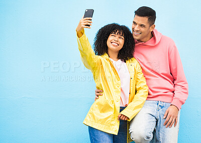 Buy stock photo Friends, phone and smile for selfie on a blue background for fashion, style or friendship together. Young man and woman smiling and looking at smartphone for photo leaning on a wall mockup