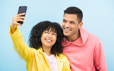 Buy stock photo Friends, phone and face with smile for selfie on a blue background for fashion, style or friendship together. Young man and woman smiling in happiness looking at smartphone for happy photo moments