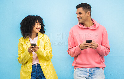 Buy stock photo Friends, phone and smile for social media, conversation or communication against a blue studio background. Happy man and woman smiling for networking, 5G connection or chatting on mobile smartphone