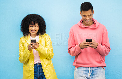 Buy stock photo Happy couple, bonding and phone typing on isolated blue background on social media, dating app or travel networking. Smile, man or black woman on mobile technology or community communication website
