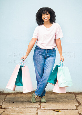 Buy stock photo Shopping, retail and portrait of a woman with bags from a sale on a blue city wall in Greece. Fashion, product and girl shopper carrying content from a shop, boutique or store downtown with a smile