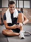 Fitness, man and phone with smile for social media, conversations or chatting while sitting on a mat at gym. Happy sporty male, person or guy smiling in happiness on smartphone after intense workout
