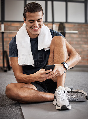 Buy stock photo Fitness, man and phone with smile for social media, conversations or chatting while sitting on a mat at gym. Happy sporty male, person or guy smiling in happiness on smartphone after intense workout