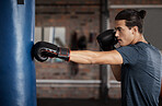 Boxing, exercise and man with focus for fight training and gym fitness ready for sports. Workout, wellness and health club with a young male athlete and boxer in a ring with punching bag alone
