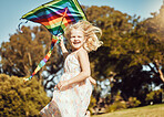 Kite, running and girl run in an outdoor park with summer fun and smile. Nature, kids vacation and happiness of kids in sunshine with freedom and smiling bonding together on green grass with blue sky