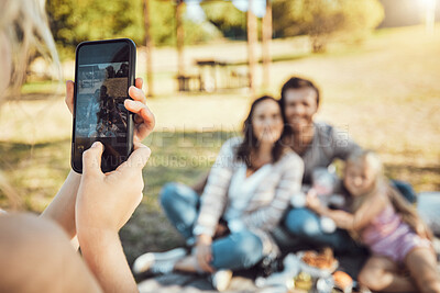 Buy stock photo Hands, phone and family photo of photographer capturing moments together for summer vacation in a park. Hand of person taking a picture of happy mother, father and daughter in nature with smartphone