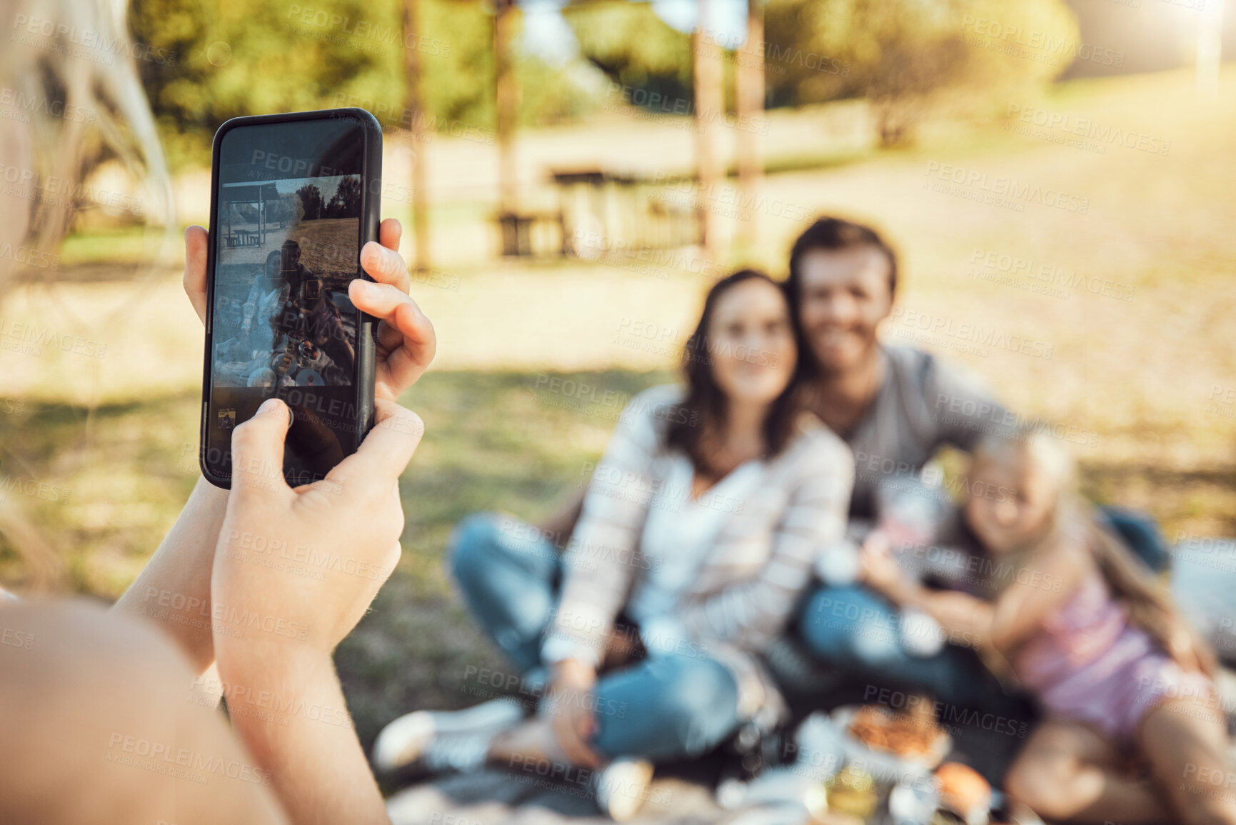 Buy stock photo Hands, phone and family photo of photographer capturing moments together for summer vacation in a park. Hand of person taking a picture of happy mother, father and daughter in nature with smartphone