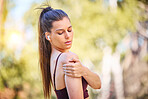 Woman runner, nature and shoulder pain on park path for fitness, health or rest by trees to massage. Outdoor training, running and relax in woods for muscle pain emergency, anatomy problem or workout