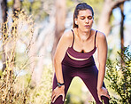 Woman runner, rest and breathing at nature park path for fitness, health or self care by trees. Outdoor training, running and relax in woods for wellness, strong body or muscle development training