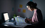 Student, reading notebook and studying at night with laptop of learning, education or internet project. Young woman, research paper and writing at dark desk for planning college homework in dormitory