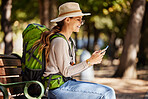 Woman, backpack or phone in travel, sightseeing or adventure in nature park, trees forest or Canada woods. Smile, happy or tourist on mobile technology for gps map, location or hiking path research