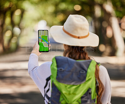 Buy stock photo Navigation, phone and woman hiking in a forest for exercise, adventure or wellness in nature. GPS app, direction and female hiker trekking on an outdoor trail in the woods alone with a mobile map.