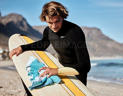 Buy stock photo Surfing, man with surfboard on beach with fitness and travel, cleaning board and surf maintenance with extreme sport outdoor. Ocean. nature and workout, young surfer lifestyle and sports motivation