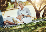 Retirement, love and picnic with a senior couple outdoor in nature to relax on a green field of grass together. Happy, smile and date with a mature man and woman bonding outside for romance
