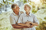 Love, hug or old couple in a park or nature bonding or holding hands in a happy marriage partnership. Retirement, senior man or romantic elderly woman hugging together in a relaxing holiday vacation