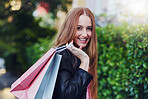 Portrait, shopping or retail and a woman customer outdoor with a smile after finding a fashion sale or deal in the city. Market, store or summer with an attractive young female consumer carrying bags
